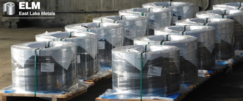 Warehouse photo from East Lake Metals showcasing rows of high-grade, palletized metal coils wrapped for industrial shipment to highlight the structural and logistical benefits of aluminum and steel for commercial building envelopes.