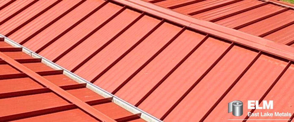Close-up view of a vibrant, terracotta-red standing seam metal roof, demonstrating the technical prepainted metal color retention provided by East Lake Metals.
