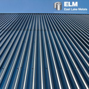 An upward-angle perspective of a dark blue corrugated steel roof, showcasing the uniform appearance and gloss retention delivered by high-durability UV resistant coatings from East Lake Metals.
