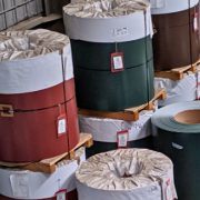 Large industrial metal coils in various colors and finishes at an East Lake Metals facility, representing the choice between aluminum vs steel for construction projects.